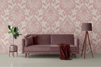 Pink floral traditional wallpaper with a pink sofa, lamp, and plant in a room.